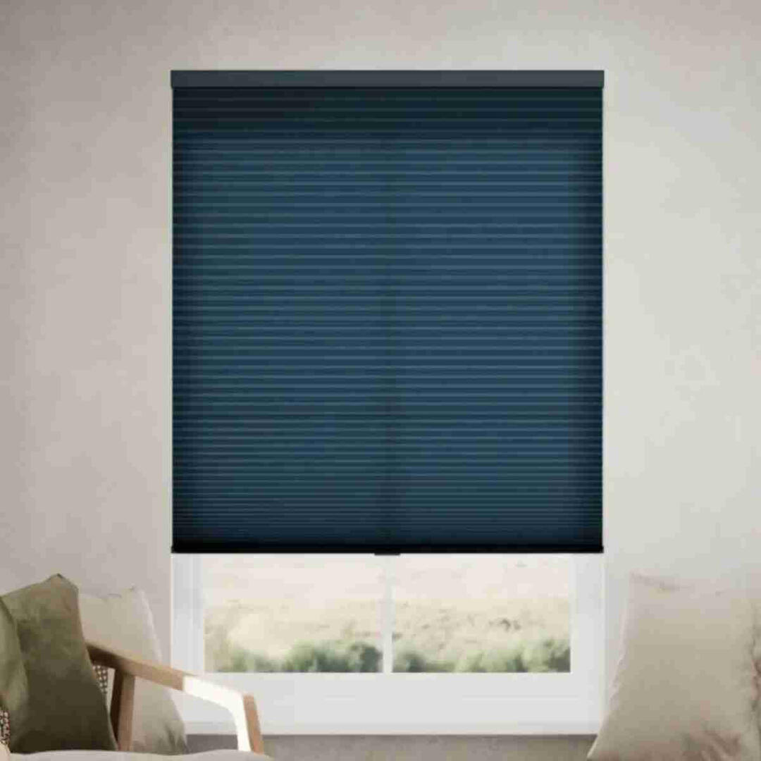 Sophisticated navy blue filtering cellular shades with a honeycomb texture installed on a window in a bright, modern living room.